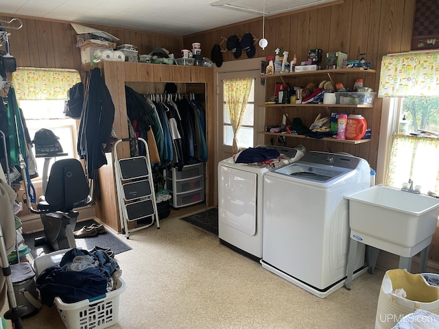 laundry area featuring washing machine and dryer, sink, and wooden walls