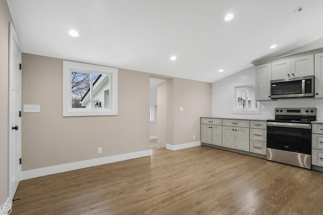 kitchen with white cabinetry, appliances with stainless steel finishes, vaulted ceiling, and light wood-type flooring