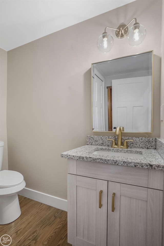 bathroom with hardwood / wood-style flooring, vanity, and toilet