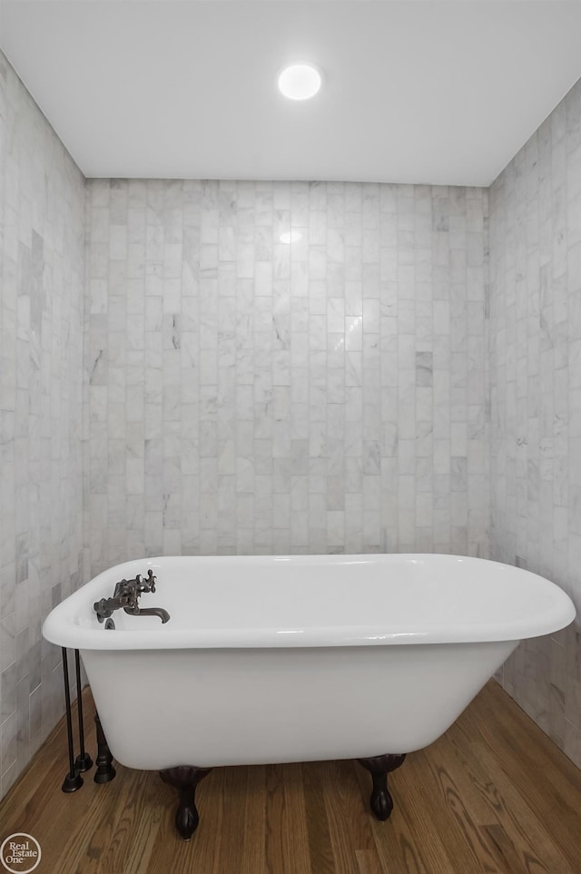 bathroom with tile walls and a tub