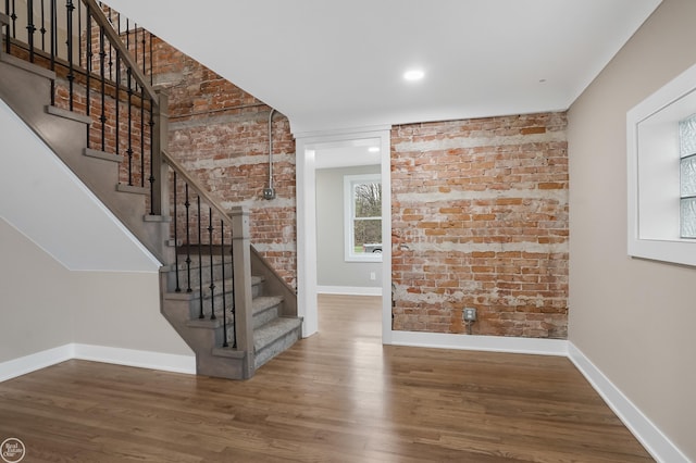 stairway featuring hardwood / wood-style flooring and brick wall