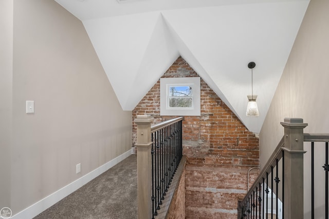 stairway with vaulted ceiling, brick wall, and carpet flooring