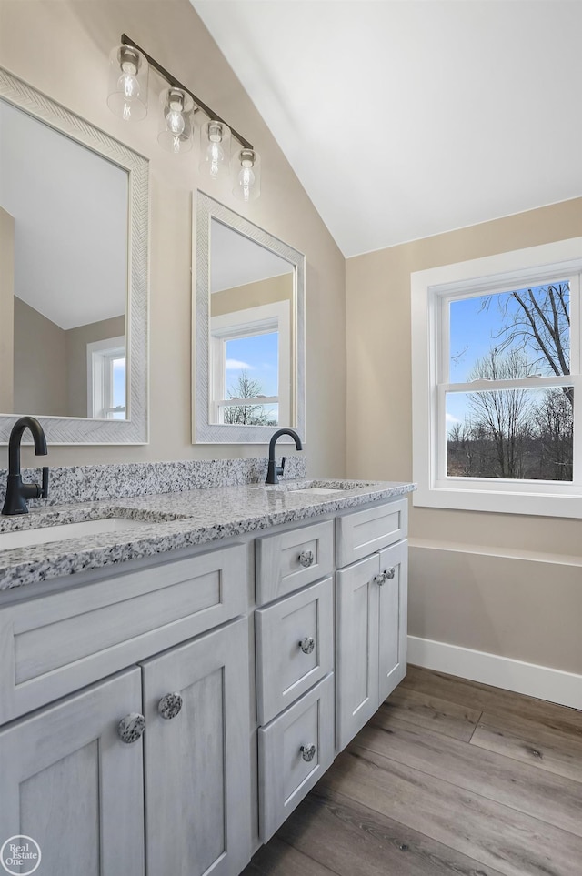 bathroom with hardwood / wood-style flooring, vanity, vaulted ceiling, and a wealth of natural light