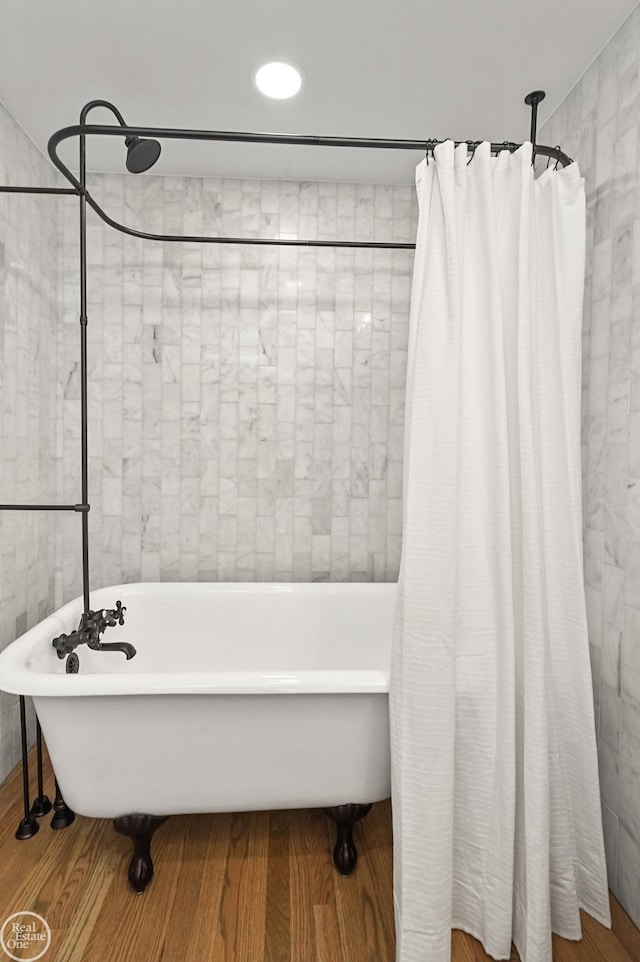 bathroom featuring a tub to relax in, wood-type flooring, and tile walls