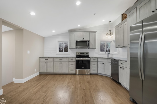 kitchen featuring sink, hanging light fixtures, light hardwood / wood-style floors, stainless steel appliances, and light stone countertops