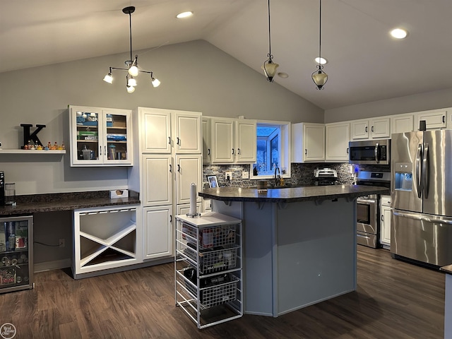 kitchen featuring a kitchen bar, backsplash, stainless steel appliances, decorative light fixtures, and white cabinetry