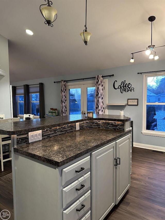 kitchen featuring white cabinetry, dark wood-type flooring, dark stone countertops, pendant lighting, and a kitchen island