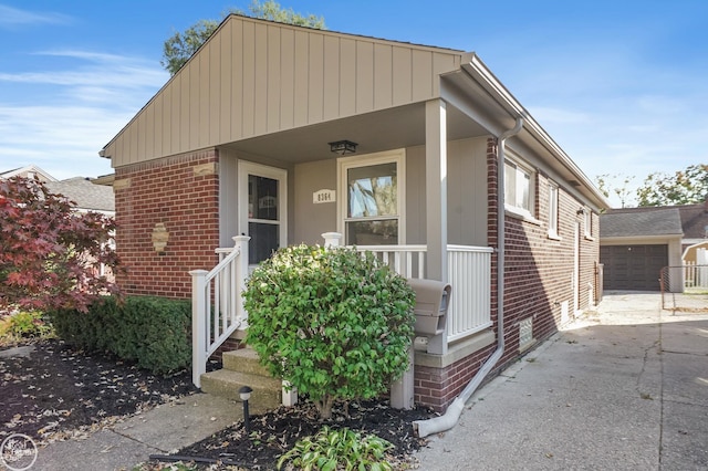 bungalow-style home with a porch, a garage, and an outdoor structure