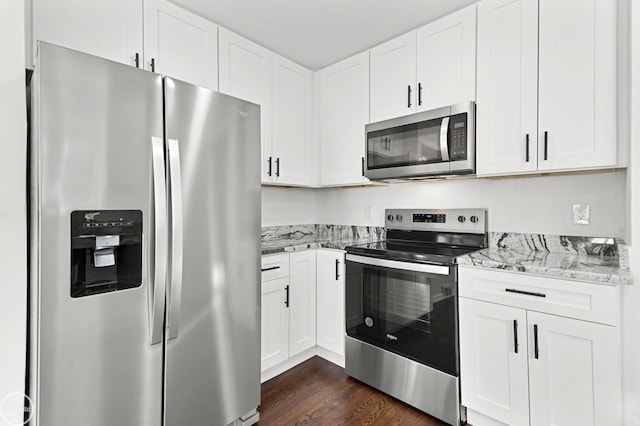 kitchen with light stone countertops, white cabinets, dark hardwood / wood-style floors, and appliances with stainless steel finishes