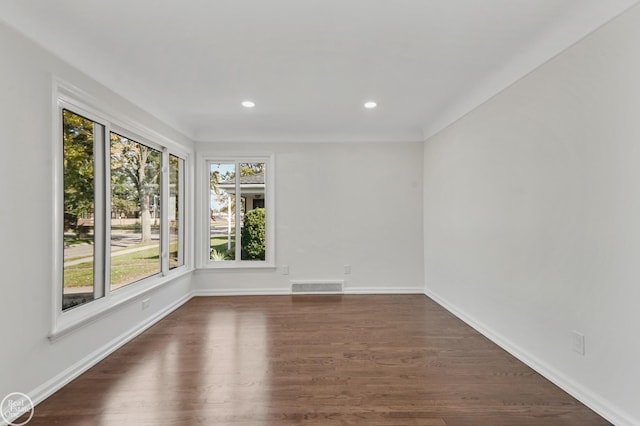 empty room with a healthy amount of sunlight and dark hardwood / wood-style flooring