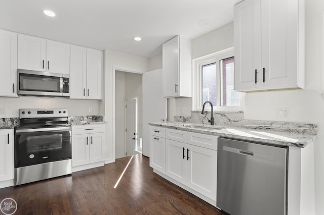 kitchen with white cabinetry, sink, light stone countertops, dark wood-type flooring, and appliances with stainless steel finishes