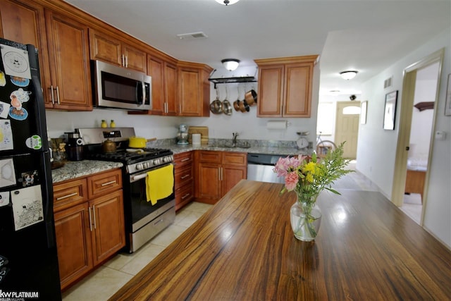 kitchen featuring light tile patterned floors, light stone countertops, sink, and appliances with stainless steel finishes