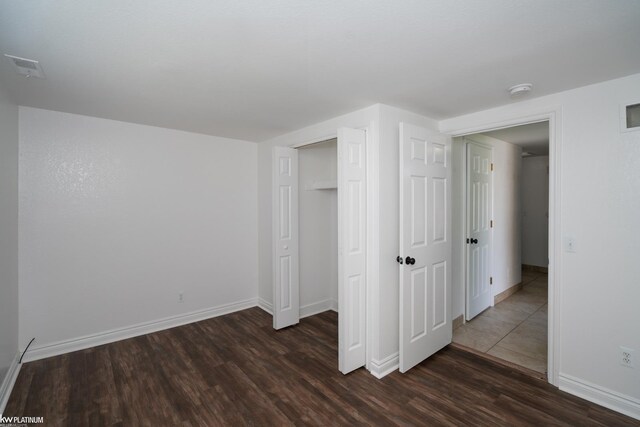 unfurnished bedroom featuring a closet and dark wood-type flooring