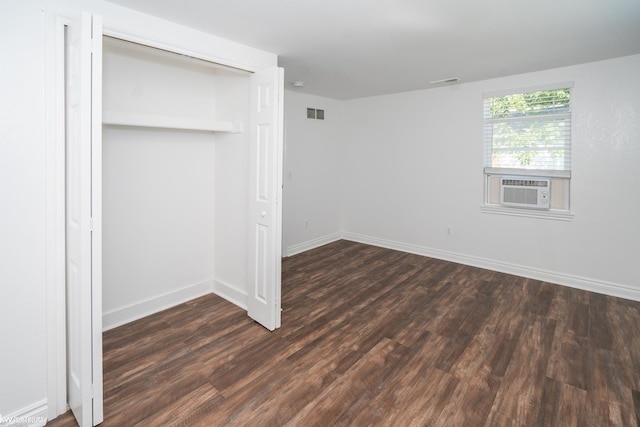 unfurnished bedroom with dark hardwood / wood-style flooring, a closet, and cooling unit