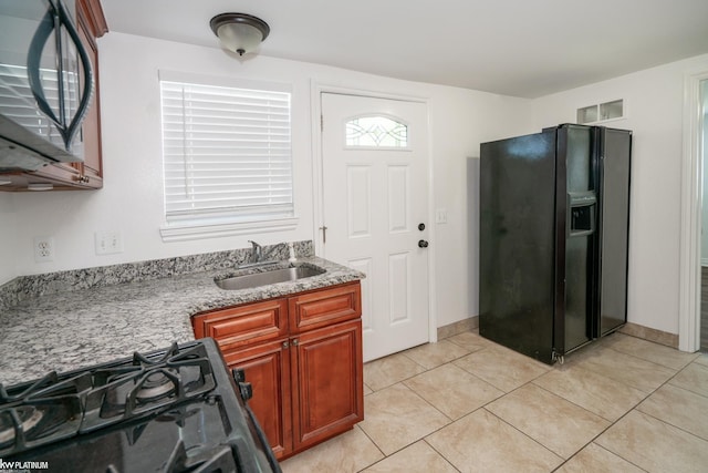 kitchen with sink, light tile patterned flooring, and black appliances