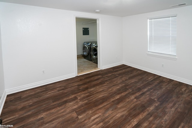 unfurnished room featuring washer and dryer, dark hardwood / wood-style flooring, and electric panel