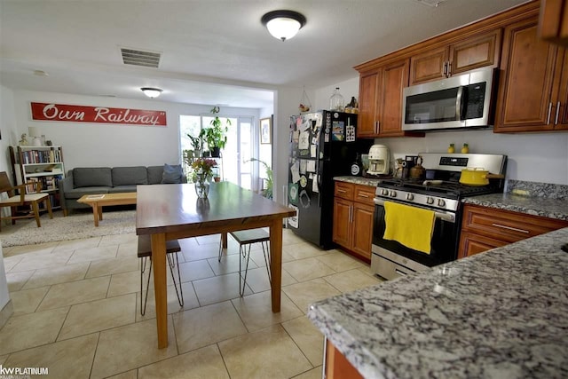 kitchen featuring light tile patterned floors, dark stone counters, and appliances with stainless steel finishes