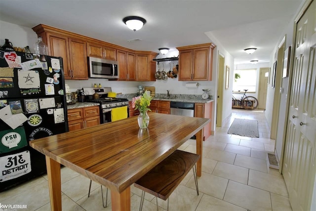 kitchen featuring sink, light stone countertops, light tile patterned floors, and stainless steel appliances