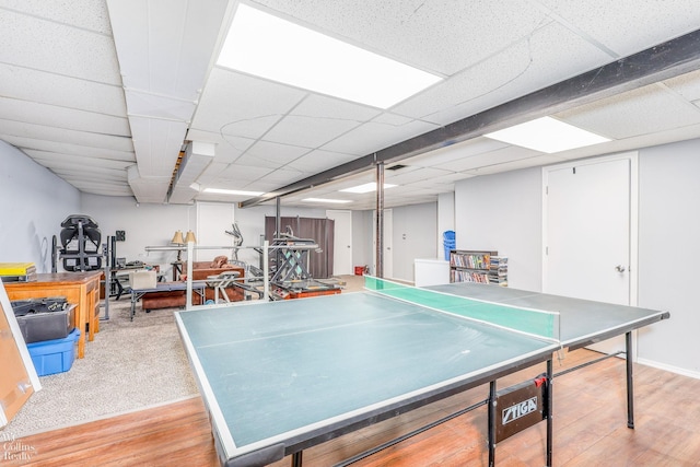 game room featuring light hardwood / wood-style floors and a drop ceiling