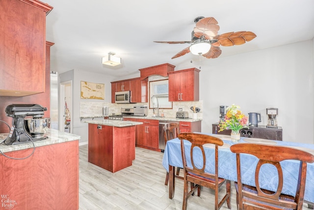 kitchen featuring backsplash, stainless steel appliances, ceiling fan, light hardwood / wood-style flooring, and a kitchen island