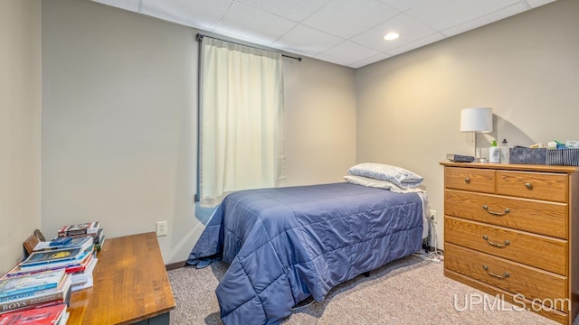 bedroom with a drop ceiling and light colored carpet