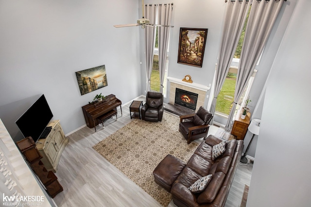 living room with ceiling fan, light hardwood / wood-style floors, and a tile fireplace