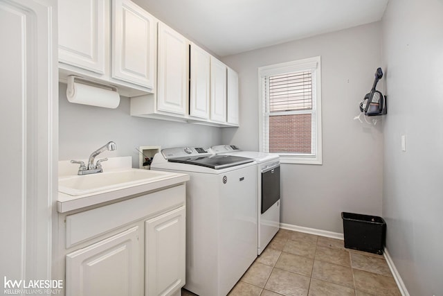 laundry area with cabinets, light tile patterned floors, sink, and washing machine and clothes dryer