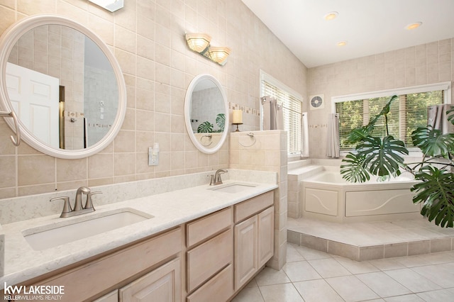 bathroom with a washtub, vanity, tile patterned flooring, and tile walls