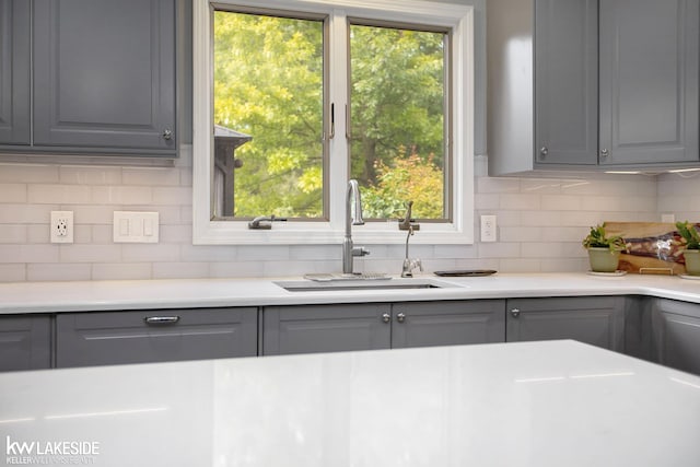 kitchen featuring backsplash, gray cabinets, and sink