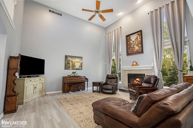 living room with a fireplace, light wood-type flooring, high vaulted ceiling, and ceiling fan