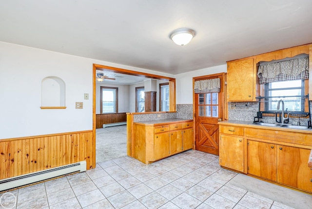 kitchen with backsplash, ceiling fan, sink, and a baseboard heating unit