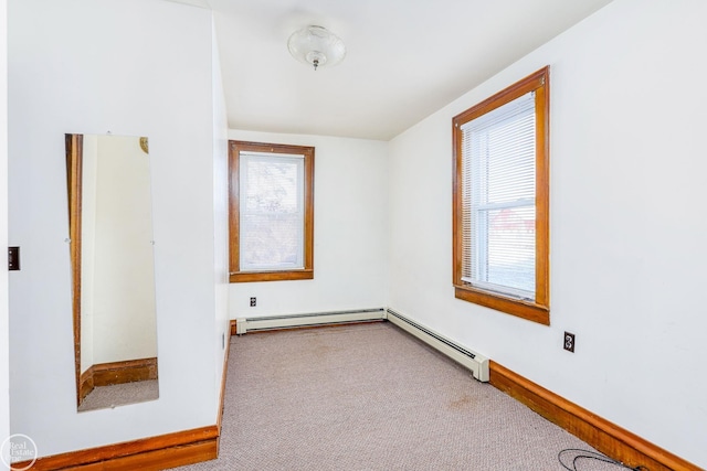 carpeted spare room featuring a baseboard radiator and a healthy amount of sunlight