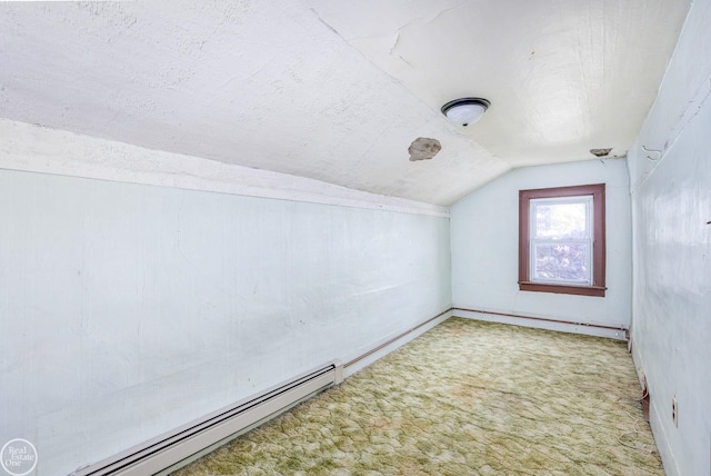 additional living space featuring a textured ceiling, carpet floors, baseboard heating, and vaulted ceiling