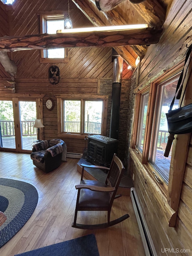 interior space with baseboard heating, beam ceiling, high vaulted ceiling, hardwood / wood-style floors, and a wood stove