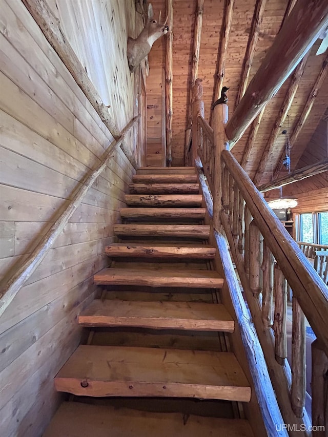 stairway featuring beam ceiling, wood walls, and wood ceiling