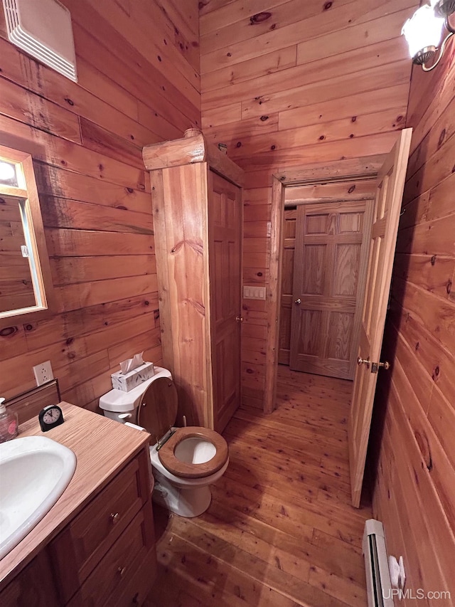 bathroom featuring vanity, wood walls, toilet, and a baseboard heating unit