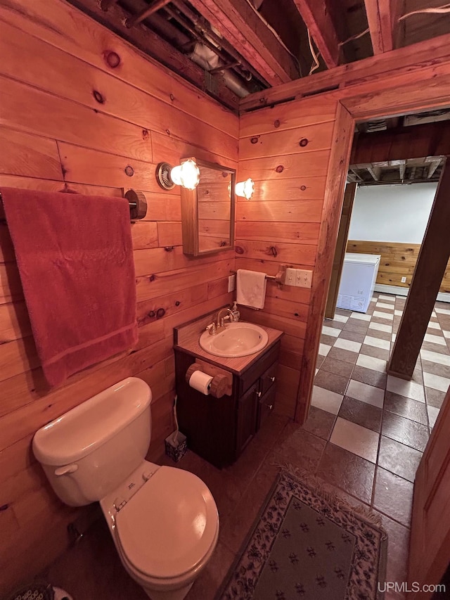 bathroom featuring wood walls, vanity, and toilet