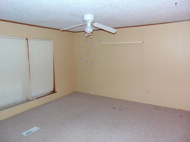 empty room with ceiling fan, a textured ceiling, and ornamental molding