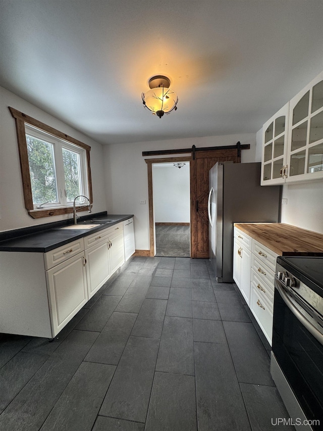 kitchen featuring white cabinets, a barn door, appliances with stainless steel finishes, and sink