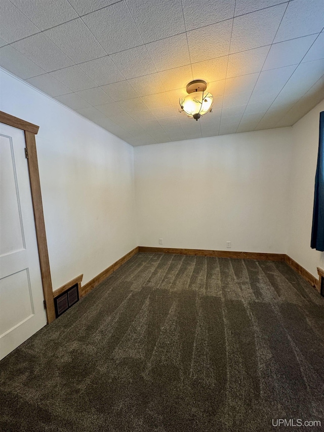 unfurnished room featuring dark colored carpet