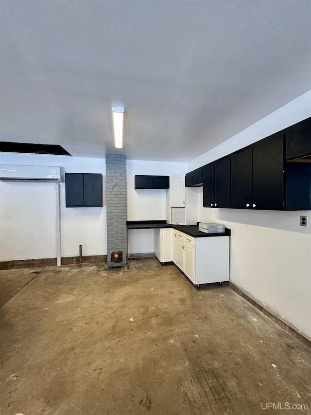 kitchen featuring concrete floors, white cabinetry, and a wall unit AC