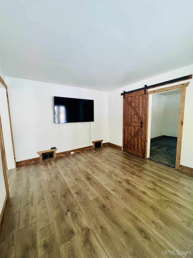 unfurnished living room featuring hardwood / wood-style flooring and a barn door