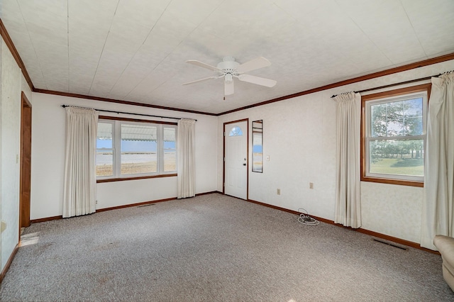 empty room with ceiling fan, crown molding, carpet floors, and a healthy amount of sunlight