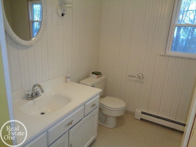 bathroom featuring vanity, wood walls, toilet, and a baseboard heating unit