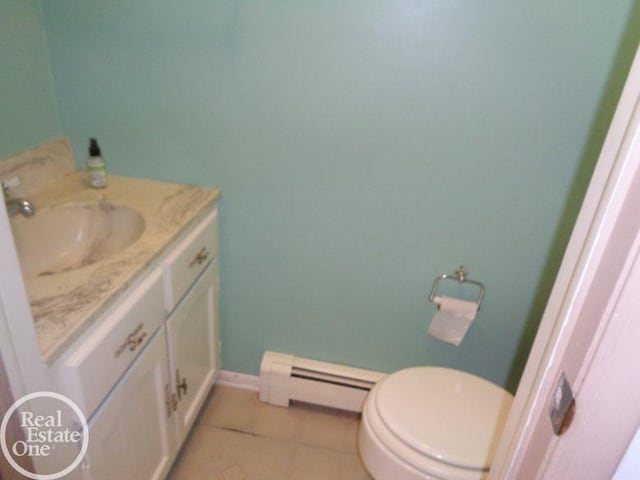 bathroom with toilet, vanity, tile patterned floors, and baseboard heating