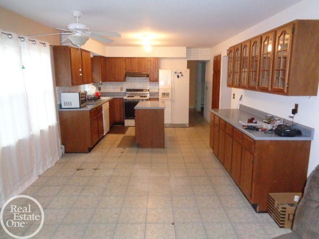 kitchen featuring ceiling fan, a center island, and white appliances