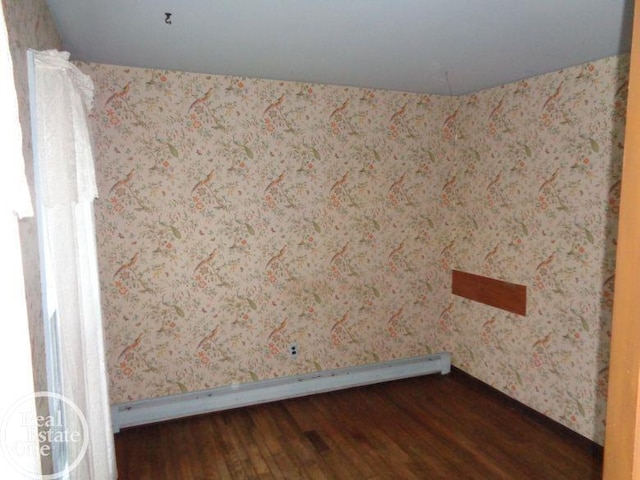 spare room with a baseboard radiator and dark hardwood / wood-style floors