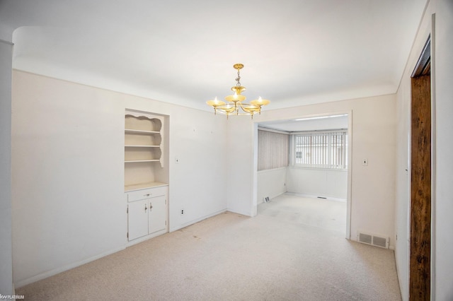 empty room with light carpet and a chandelier