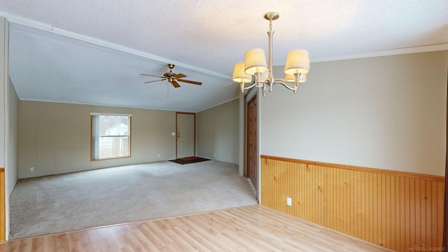 empty room with lofted ceiling with beams, hardwood / wood-style floors, a textured ceiling, wooden walls, and ceiling fan with notable chandelier