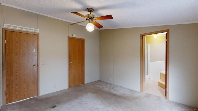 unfurnished bedroom featuring ensuite bathroom, ceiling fan, ornamental molding, a textured ceiling, and light colored carpet